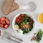 Top view of a nutritious breakfast with salad, eggs, bread, and juice, perfect for a healthy start.